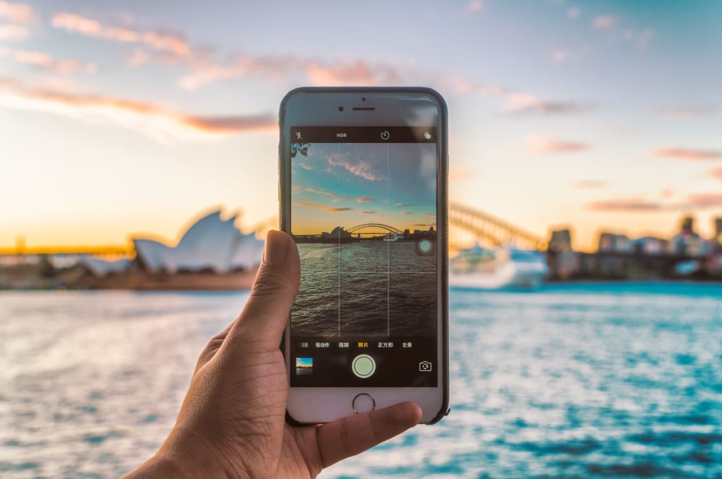 Person taking picture of Sydney Opera House on phone